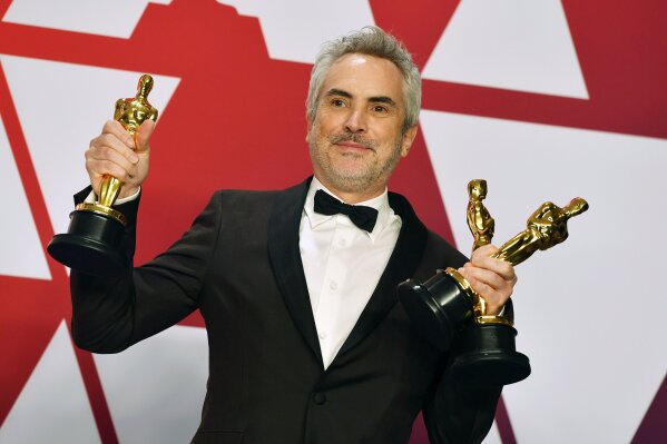 
              FILE - In this Sunday, Feb. 24, 2019, file photo, Alfonso Cuaron poses with the awards for best director for "Roma," best foreign language film for "Roma," and best cinematography for "Roma" in the press room at the Oscars at the Dolby Theatre in Los Angeles. “Roma” may not have won the best picture Oscar this year, but it came close enough to make some of Hollywood’s top players worry about Netflix’s infiltration of their most prestigious award. (Photo by Jordan Strauss/Invision/AP, File)
            