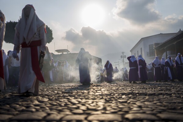 Penitents known as cucuruchos burn incense during a Holy Week procession, marking the start of Holy Week in Antigua, Guatemala, on Palm Sunday, March 24, 2024. (AP Photo/Moises Castillo)