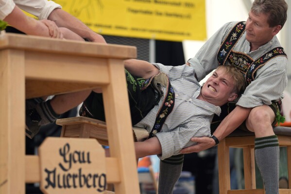 A man dressed in traditional clothes tries to pull his opponent over the table at the German Championships in Fingerhakeln or finger wrestling, in Bernbeuren, Germany, Sunday, May 12, 2024. Competitors battled for the title in this traditional rural sport where the winner has to pull his opponent over a marked line on the table. (Ǻ Photo/Matthias Schrader)