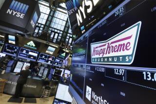 FILE - The Krispy Kreme logo appears above its trading post on the floor of the New York Stock Exchange, Monday, May 9, 2016. Krispy Kreme will pay nearly $1.2 million in back wages and damages to workers to resolve overtime pay violations under a settlement announced Thursday, Nov. 17, 2022, by the U.S. Department of Labor.   (AP Photo/Richard Drew, File)