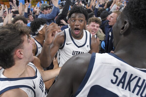 Utah State forward Great Osobor, center, celebrates with players and fans after the team's win over Colorado State in an NCAA college basketball game Saturday, Jan. 6, 2024, in Logan, Utah. (Eli Lucero/The Herald Journal via AP)