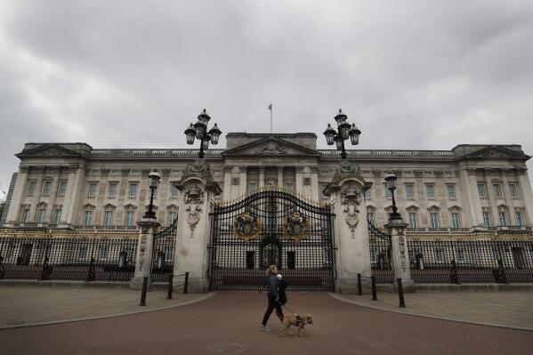 FILE - A dog walker passes a quiet Buckingham Palace, in London, March 23, 2021. Royal accounts show the British monarchy’s publicly-funded spending rose to 102.4 million pounds ($124 million) in the past year, with the renovation of Buckingham Palace taking up a large part of the expenses. The palace’s annual Sovereign Grant report showed that royal spending went up by 14.9 million pounds, or 17%, compared to the previous year, a report published Thursday, June 30, 2022 showed. (AP Photo/Kirsty Wigglesworth, file)