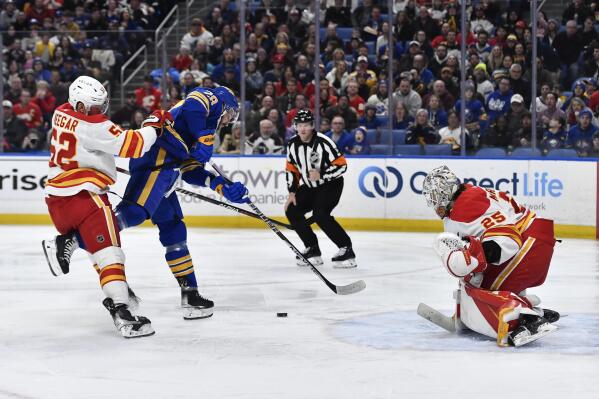 Buffalo Sabres left wing Zemgus Girgensons, center, is tied up with Calgary Flames defenseman MacKenzie Weegar, left, while trying to get a shot off on goalie Jacob Markstrom during the second period of an NHL hockey game in Buffalo, N.Y., Saturday, Feb. 11, 2023. (AP Photo/Adrian Kraus)