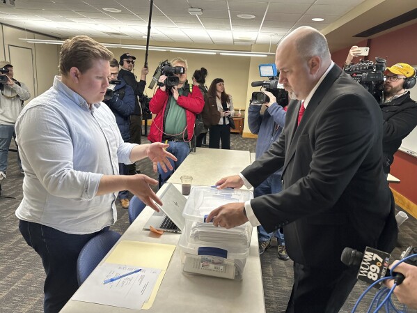 Matthew Snorek, right, submits petitions to force a recall election targeting Wisconsin's top elected Republican, Assembly Speaker Robin Vos, Monday, March 11, 2024, in Madison, Wis. Vos angered backers of former President Donald Trump when he refused to impeach the official who oversees the battleground state's elections. (AP Photo/Scott Bauer)