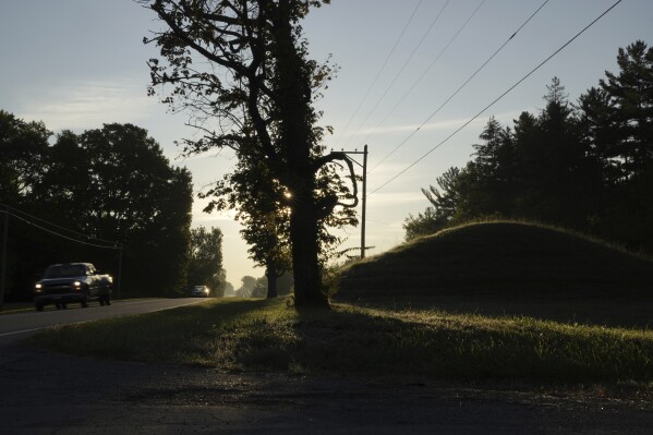 Cars drive along a road near one of the Twin Mounds, at right, at Fort Ancient Earthworks, Tuesday, Sept. 19, 2023, in Oregonia, Ohio. Fort Ancient is part of a network of ancient American Indian ceremonial and burial mounds around Ohio that were added to the list of UNESCO World Heritage sites. (AP Photo/Joshua A. Bickel)