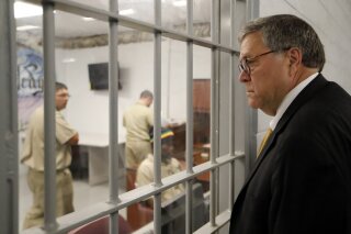 FILE - In this July 8, 2019, file photo, Attorney General William Barr watches as inmates work in a computer class during a tour of a federal prison. in Edgefield, S.C. The Justice Department is making changes to its system used to identify whether an inmate is likely to commit crimes again after release from prison to ensure the process is fair and effective. It's part of a sweeping criminal justice overhaul measure that was enacted last year. The federal Bureau of Prisons has already assessed nearly all of the 175,269 inmates in federal custody. But the Justice Department plans to re-screen all of those inmates under new guidelines, which officials say places a stronger emphasis on accurately measuring an inmate’s change behind bars. (AP Photo/John Bazemore, File)