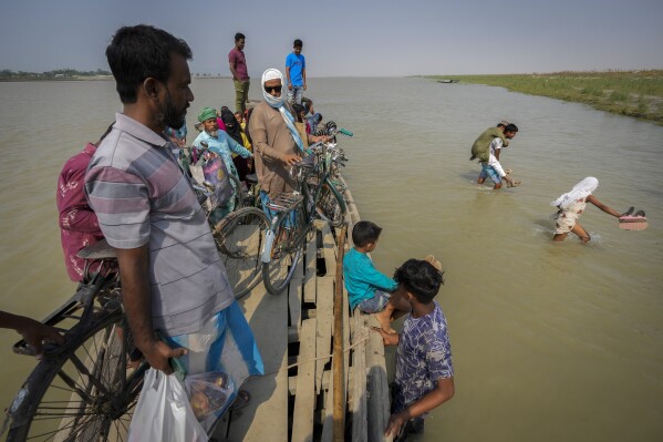 People travel on a boat to a polling station across the Brahmaputra river on the eve of the second phase of the national election in Morigaon district, near Guwahati, India, Thursday, April 25, 2024. Voters in India, from the rain-drenched Himalayas in the north to the sweltering, dry south, are looking for politicians who promise relief, stability and resilience to the wide-ranging and damaging effects of a warming climate. But experts and voters say there has been little talk about climate change on the campaign trail. (AP Photo/Anupam Nath)