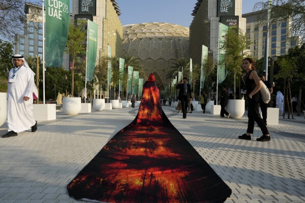 Islene Facanha, of Portugal, participates in a demonstration dressed with images of wildfires at the COP28 U.N. Climate Summit, Dec. 8, 2023, in Dubai, United Arab Emirates. (AP Photo/Peter Dejong)