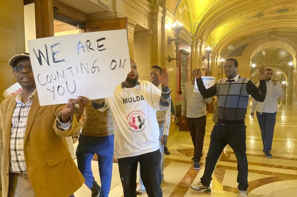 Supporters of Minnesota legislation -- which would require ride-hailing companies to increase pay for drivers -- walk through the State Capitol building, holding signs that say "WE ARE COUNTING ON YOU" and shirts that say "MULDA Minnesota Uber/Lyft Driver Association," in St. Paul, Minn.,, May 17, 2024. Uber and Lyft have said they will leave the state if Minnesota lawmakers pass legislation that requires the companies to raise driver pay by more than they want to. (AP Photo/Trisha Ahmed)