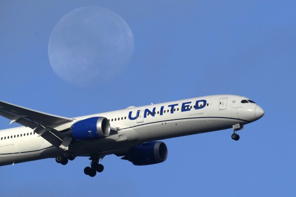 FILE - A United Airlines Boeing 787 approaches for landing in Lisbon, Sept. 2, 2023, with the setting moon in the background. United Airlines reports their earnings on Tuesday, april 16, 2024. (AP Photo/Armando Franca, File)