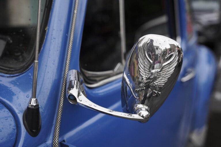 The bright blue Volkswagen Beetle owned by taxi driver Claudio Garcia he named "Gualupita" behind his wife, there's a custom side-view mirror, in the Cuautepec neighborhood of Mexico City, Friday, June 21, 2024. As some of the older Beetles rock together, the paint long faded from years of wear and tear, other drivers how Garcia dresses their cars, keeping them in good shape.  (AP Photo/Aurea Del Rosario)