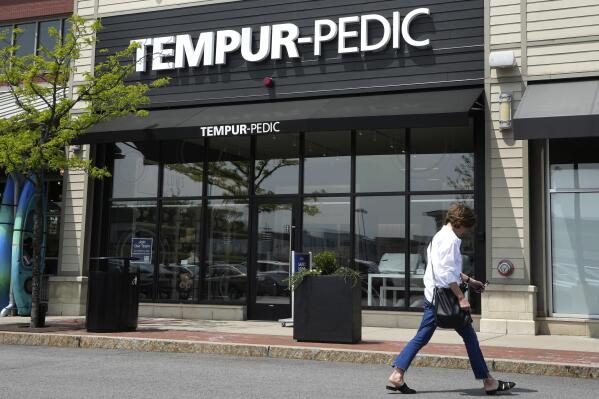 A passer-by walks near the front of a Tempur-Pedic mattress store location, Tuesday, May 9, 2023, in Dedham, Mass. Tempur Sealy, the parent company of Tempur-Pedic, has agreed to acquire Mattress Firm in a cash-and-stock transaction valued at about $4 billion. The companies said Tuesday they expect to complete the transaction in the second half of 2024. (AP Photo/Steven Senne)