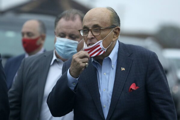 Former New York Mayor Rudy Giuliani lowers his face mask as he approaches supporters Monday, Oct. 12, 2020 during a Columbus Day gathering at a Trump campaign field office in Philadelphia. (AP Photo/Jacqueline Larma)