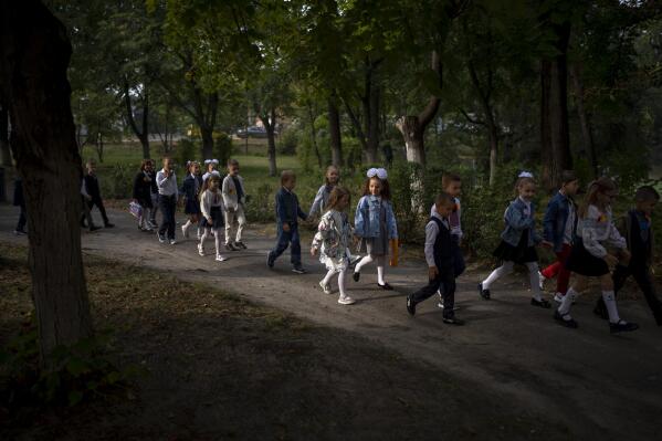 Students walk together entering in their class during their first day of school at a public school in Irpin, Ukraine, Thursday, Sept. 1, 2022. Ukrainian children return to school without sharing memories from their holidays. They share stories of how they survived the first months of the war. For many children, last semester finished the day before Russia invaded Ukraine on the 24th of February. The ongoing war remains the biggest challenge for the educational system of Ukraine. (AP Photo/Emilio Morenatti)