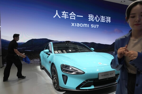The Xiaomi SU7 is displayed with the slogan, "The car and the person as one, my heart is surging," in Beijing, Thursday, April 25, 2024. China's vision of the future of the automobile — electrified and digitally connected — is on display at the ongoing Beijing auto show. (AP Photo/Ng Han Guan)
