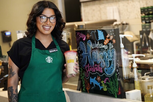 Valencia Villanueva poses for a photo with a reusable cup at an Arizona State University Starbucks shop Wednesday, June 7, 2023, in Tempe, Ariz. Villanueva has noted a growing consciousness among customers about the cup-washing machine and the "borrowed" cup program. (AP Photo/Ross D. Franklin)