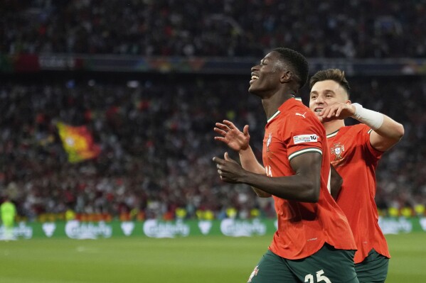 Portugal's Nuno Mendes, left, celebrates with Portugal's Francisco Conceicao after scoring his sides first goal during the Nations League final soccer match between Portugal and Spain at the Allianz Arena in Munich, Germany, Sunday, June 8, 2025. (AP Photo/Matthias Schrader)