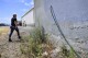 Code enforcement officer Jesalyn Harper walks past the garden hose which tipped her off to an illegal medical lab owned by Chinese business people that was operating inside an old warehouse in Reedley, Calif., on Aug. 1, 2023. (Eric Paul Zamora/The Fresno Bee via AP)