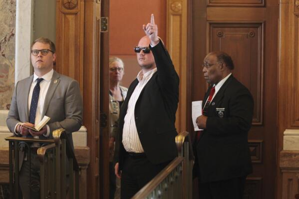 Kansas state Rep. Adam Thomas, R-Olathe, signals his vote in favor of overriding a veto from Gov. Laura Kelly of an anti-abortion bill from the back of the chamber, Wednesday, April 26, 2023, at the Statehouse in Topeka, Kansas. Thomas spent only brief moments in the chamber because a line drive hit him directly in the face while he was pitching during a recent softball game, resulting in serious injuries. (AP Photo/John Hanna)