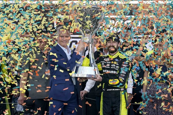 Ryan Blaney, center right, receives the NASCAR Cup Series Championship Cup from NASCAR president Steve Phelps, center left, after winning it at Phoenix Raceway, Sunday, Nov. 5, 2023, in Avondale, Ariz. (AP Photo/Darryl Webb)