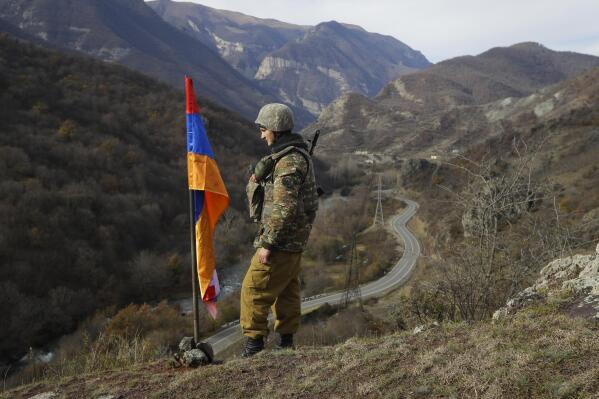 FILE - In this Wednesday, Nov. 25, 2020 file photo, An ethnic Armenian soldier stands guard next to Nagorno-Karabakh's flag atop of the hill near Charektar in the separatist region of Nagorno-Karabakh at a new border with Kalbajar district turned over to Azerbaijan. Armenia’s Defense Ministry is reporting that three of its troops were killed and two more were wounded in clashes with Azerbaijani forces on the border between the two ex-Soviet nations. The two countries have been locked in a decades-long tug-of-war over the Nagorno-Karabakh region, and they accused each other of starting the clashes on Wednesday, July 28, 2021. (AP Photo/Sergei Grits, File)