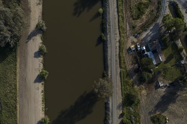 A home sits next to the North Fork Kings River in the Island District of Lemoore, Calif., Wednesday, April 19, 2023. Residents in rural communities in the heart of the state are facing the prospect of being marooned by rising rivers or flooded out. (AP Photo/Jae C. Hong)