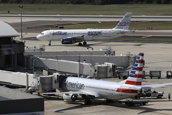 FILE - A JetBlue Airbus A320 taxis to a gate on Oct. 26, 2016, after landing, as an American Airlines jet is seen parked at its gate at Tampa International Airport in Tampa, Fla. The two airlines must abandon their partnership in the northeast United States, a federal judge in Boston ruled Friday, May 19, 2023, saying that the government proved that the deal reduces competition in the airline industry. (AP Photo/Chris O'Meara, File)