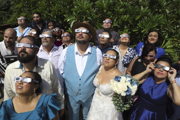 Isaac Medina, center, and Jazmin Gonzalez, center right, watch a "ring of fire" solar eclipse before their wedding ceremony in Merida, Mexico, Saturday, Oct. 14, 2023. The annular eclipse dimmed the skies over parts of the western U.S. and Central and South America. (AP Photo/Martin Zetina)