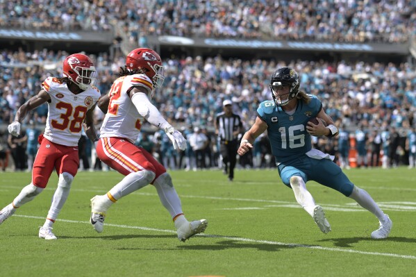 Jacksonville Jaguars quarterback Trevor Lawrence (16) scrambles as he is pressured by Kansas City Chiefs cornerback L'Jarius Sneed (38) and linebacker Nick Bolton (32) during the second half of an NFL football game, Sunday, Sept. 17, 2023, in Jacksonville, Fla. (AP Photo/Phelan M. Ebenhack)