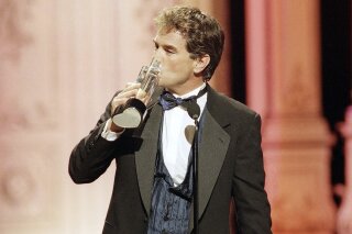 FILE - In this Friday, Feb. 27, 1998 file photo, John Callahan of "All My Children" kisses his award after winning Outstanding Lead Actor at the Soap Opera Digest Awards in Universal City, Calif. Callahan, known for playing Edmund Grey on “All My Children” and also starring on other soaps including “Days of Our Lives,” “Santa Barbara” and “Falcon Crest,” has died. He was 66. His ex-wife and former co-star Eva LaRue announced his death on her social media account on Saturday, March 28, 2020. (AP Photo/Rene Macura)