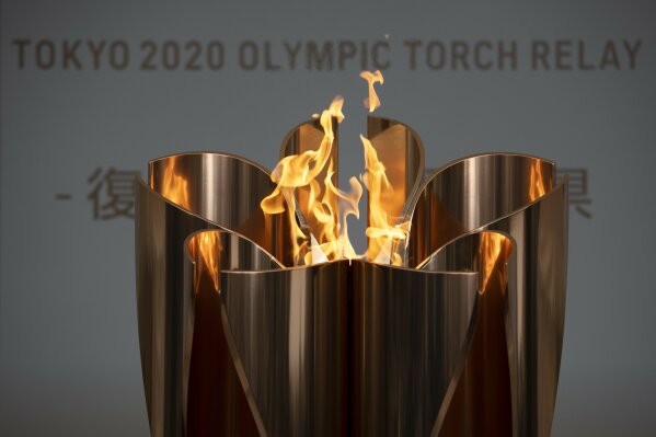 FILE - In this March 24, 2020, file photo, the Olympic Flame burns during a ceremony in Fukushima City, Japan. The Tokyo Olympics were postponed a month ago. But there are still more questions than answers about the new opening on July 23, 2021 and what form those games will take.(AP Photo/Jae C. Hong, File)