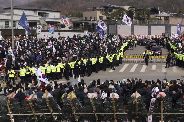 A vehicle carrying South Korea's former President Park Geun-hye arrives her home as supporters and local residents wave national flags upon arrival in Daegu, South Korea, Thursday, March 24, 2022. Three months after being pardoned for one of South Korea's worst government-corruption scandals, former President Park went home Thursday after being released from a hospital. (Lee Young-hwan/Newsis via AP)