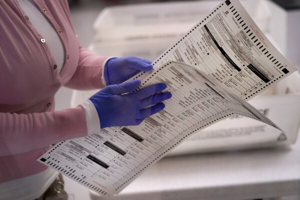 FILE - An election worker carries two ballots to be verified inside the Maricopa County Recorders Office, Nov. 10, 2022, in Phoenix. Few Republicans have high confidence that votes will be tallied accurately in next year’s presidential contest, suggesting years of sustained attacks against elections by former President Donald Trump and his allies have taken a toll. A new poll from The Associated Press-NORC Center for Public Affairs Research shows that just 22% of Republicans have high confidence in the 2024 vote count compared to 71% of Democrats. (AP Photo/Matt York, File)