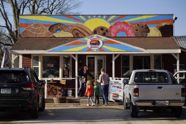 FILE - A customer holds the door for a family arriving at Leavitt's Country Bakery, Thursday, April 13, 2023, in Conway, N.H. Residents have passed a public art ordinance after a well-intentioned school art project – a large painting of pastries displayed over a roadside bakery – split the town with a legal battle pitting zoning codes against freedom-of-speech rights (AP Photo/Robert F. Bukaty)