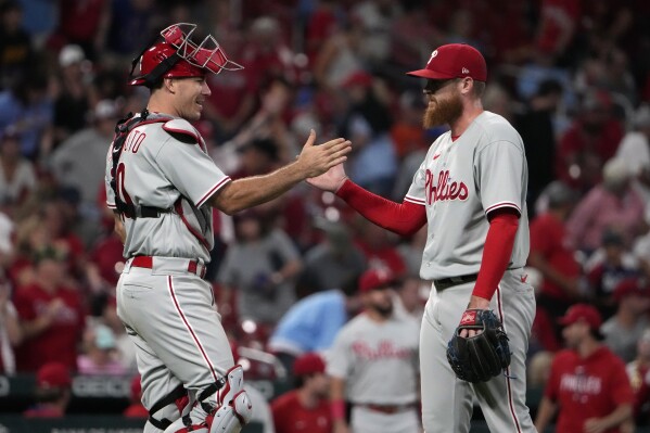 Philadelphia Phillies catcher J.T. Realmuto, left, and relief pitcher Dylan Covey celebrate a 6-1 victory over the St. Louis Cardinals following a baseball game Saturday, Sept. 16, 2023, in St. Louis. (AP Photo/Jeff Roberson)