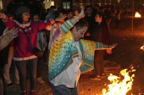 People dance while celebrating Chaharshanbe Souri, or Wednesday Feast, an ancient Festival of Fire on the eve of the last Wednesday of the Persian year, in Tehran, Iran, Tuesday, March 18, 2025. (AP Photo/Vahid Salemi)
