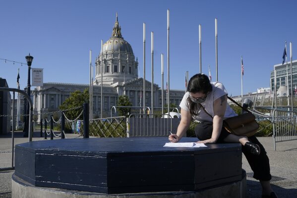 Andie Grossman fills out her ballot before delivering it to a San Francisco Department of Elections voting center in San Francisco, Sunday, Nov. 1, 2020. (AP Photo/Jeff Chiu)