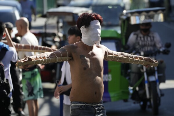 A hooded Filipino penitent carries pointed bamboo sticks as part of Holy Week rituals to atone for sins or fulfill vows for an answered prayer in metropolitan Manila, Philippines on Maundy Thursday, March 28, 2024. The bizarre lenten ritual is frowned upon by the church in this predominantly Roman Catholic country. (AP Photo/Aaron Favila)