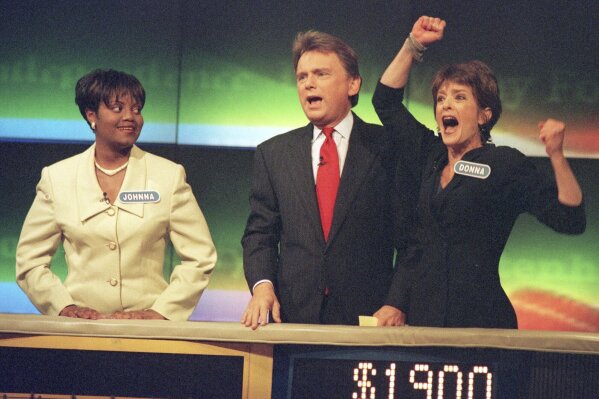 FILE - Johnna Goodwin, left, watches as Donna Handel, right, reacts after winning on "Wheel of Fortune," with host Pat Sajak during a taping of the game show in Philadelphia on April 17, 1999. The game show was in Philadelphia for the weekend taping a week's worth of shows. Ryan Seacrest will replace the retiring Sajak as host of “Wheel of Fortune.” (AP Photo/William Thomas Cain, File)