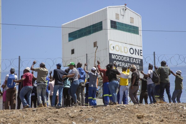 Miners gather at the top of a goldmine shaft in Springs, South Africa, Tuesday, Oct. 24, 2023. A group of miners from an unregistered, rival union are holding around 500 of their colleagues underground for the second day at the mine over a union dispute. Some 15 miners have been injured in scuffles, the head of the mine said on Tuesday.(AP Photo/Denis Farrell)