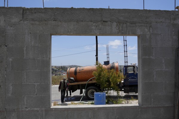Augustin Rodriguez walks from his water truck during a delivery, Tuesday, May 9, 2023, in Tijuana, Mexico. Among the last cities downstream to receive water from the shrinking Colorado River, Tijuana is staring down a water crisis. (AP Photo/Gregory Bull)