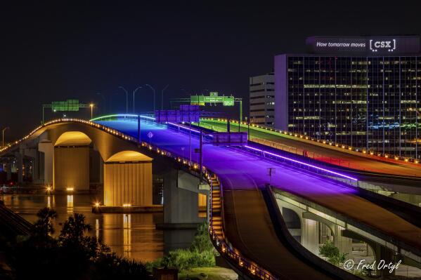 In this photo provided by the Jacksonville Transportation Authority, the Acosta Bridge is illuminated with rainbow lighting in honor of Pride Month, Monday, June 7, 2021, in downtown Jacksonville, Fla.  Florida has doused the rainbow lights temporarily decorating the bridge to celebrate gay rights, saying the decision was not motivated by animus but because the display violated regulations. The lights were turned back to blue Tuesday night, June 8.  (Fred Ortyl/ Jacksonville Transportation Authority via AP)