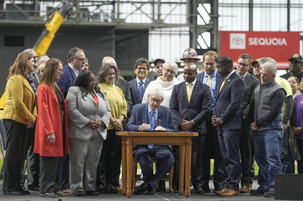 FILE - Wisconsin Governor Tony Evers signs Assembly Bill 438 and Assembly Bill 439 at American Family Field in Milwaukee, Tuesday, Dec. 5, 2023.  Proposals for new and improved sports stadiums are rising rapidly across America — and could come at a steep price for taxpayers.  (AP Photo/Maurie Gash)