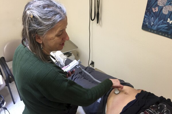 FILE - In this Dec. 21, 2016 file photo, family physician Leslie Hayes listens for a fetal heartbeat while attending to a 40-year-old mother (right, obscured) who is being treated for an addiction to heroin with the anti-craving medication Subutext, at the El Centro Family Health medical clinic in Espanola, N.M. Most New Mexico families with infants exposed to illicit drugs, marijuana and alcohol in the womb have been forgoing subsidized addiction treatment and other voluntary support services since the state's shift in 2020 that halted automatic referrals to protective services, a new study indicated on Friday, Oct. 27, 2023. (AP Photo/Morgan Lee)