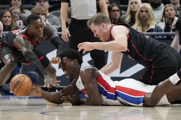 Toronto Raptors guard Dennis Schroder, left, and center Jakob Poeltl (19) reach in on Detroit Pistons center Jalen Duren during the first half of an NBA basketball game, Saturday, Dec. 30, 2023 in Detroit. (AP Photo/Carlos Osorio)