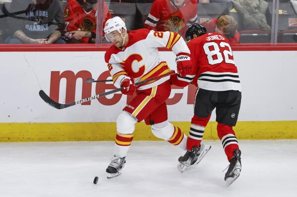 Calgary Flames center Trevor Lewis (22) battles for the puck with Chicago Blackhawks defenseman Caleb Jones (82) during the second period of an NHL hockey game, Sunday, Jan. 2, 2022, in Chicago. (AP Photo/Kamil Krzaczynski)