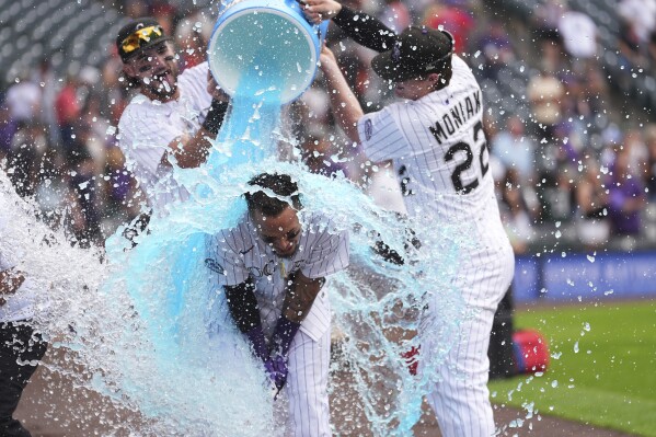 Colorado Rockies' Orlando Arcia, center, is doused by Sam Hilliard, left, and Mickey Moniak, right, after his walkoff single to drive in two runs to defeat the San Francisco Giants in a baseball game Thursday, June 12, 2025, in Denver. (AP Photo/David Zalubowski)