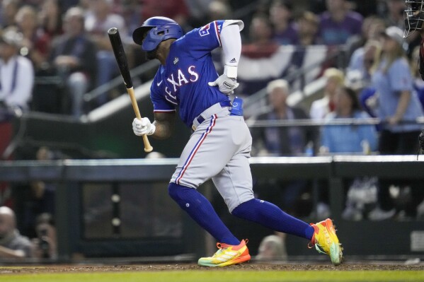 Texas Rangers' Adolis Garcia grabs his left side after his swing during the eighth inning in Game 3 of the baseball World Series against the Arizona Diamondbacks Monday, Oct. 30, 2023, in Phoenix. (AP Photo/Godofredo A. Vásquez)