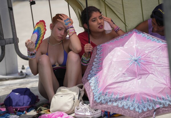 Taylor Swift fans wait for the doors of the Nilton Santos Olympic stadium to open amid a heat wave in Rio de Janeiro, Brazil, Saturday, Nov. 18, 2023. The deaths of two people, muggings and a dangerous heat wave left legions of Brazilian fans angry and disappointed in the three-day Rio leg of the pop superstar's Eras Tour. (AP Photo/Silvia Izquierdo)