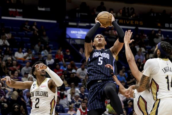 Orlando Magic forward Paolo Banchero (5) shoots over New Orleans Pelicans guard CJ McCollum (3) and forward Brandon Ingram, right, and guard Josh Richardson (2) in the second half of an NBA basketball game in New Orleans, Monday, Feb. 27, 2023. (AP Photo/Derick Hingle)